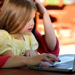 Child sitting on mother's lap while playing on the computer