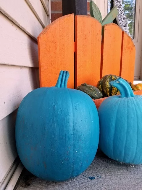 Teal pumpkins in front of an orange chair